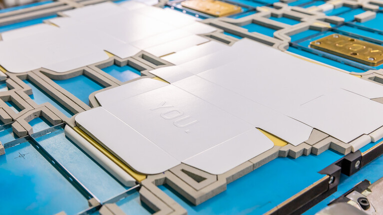 Der gestanzte Kartonage Zuschnitt mit Hochprägung liegt auf einer Marbach-Stanzform mit Prägeklischee | © Marbach Group