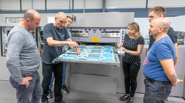 Trainer shows the participants of the paperboard compact course die-cutting and refining at the Marbach Academy how to set up a female embossing die on a cutting-die  | © Marbach Group