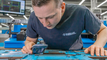 Produktionsmitarbeiter bei Marbach überprüft die Genauigkeit der Schneidlinien die er gerade montiert hat mit einer Lupe. | © Marbach Group