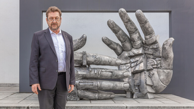 Geschäftsführender Gesellschafter Peter Marbach vor der Skulptur Incontro "Hand in Hand" von Gunther Stilling am Hauptsitz der Marbach-Gruppe in Heilbronn.  | © Marbach Group